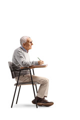 Fototapeta premium Senior man sitting in a schoolchair and writing