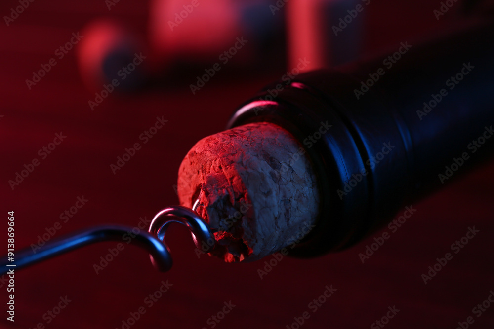 Sticker Wine bottle with corkscrew in lights on table, closeup