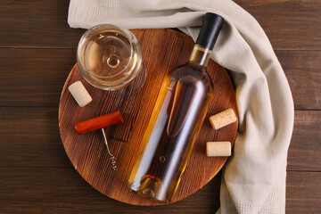 Corkscrew, glass of wine, bottle and corks on wooden table, top view