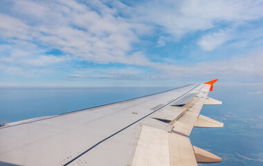 View from the airplane window at a beautiful cloudy sky and the airplane wing