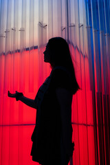 Striking silhouette of a woman illuminated by vibrant, otherworldly lighting, creating an aura of...