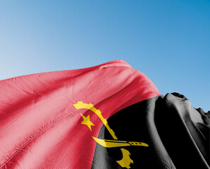Angola national flag cloth fabric waving on beautiful sky Background.