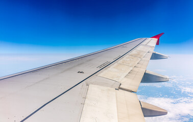 Fototapeta premium View from the airplane window at a beautiful cloudy sky and the airplane wing