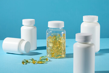 Design template of medication theme with blue background and frontal view. In the center displaying a clear supplement bottle contains yellow soft gel capsule, surrounded by white several drug jars