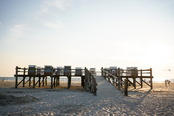 Beach baskets are neatly lined up along the sandy shore of Sankt Peter-Ording Beach, with the North...