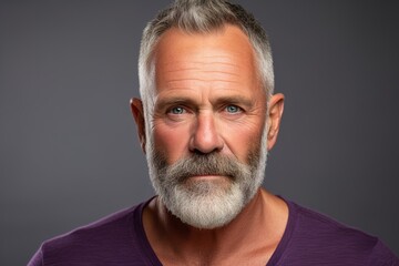 Fototapeta premium A man with a beard and gray hair is wearing a purple shirt