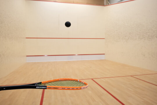 Squash racket and ball inside court, ball bouncing off the racket