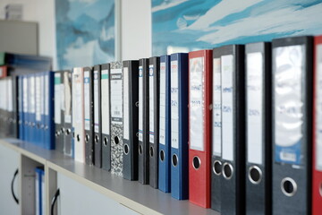 Row of used office folders or binders on a shelf. Close up shot, shallow depth of field, no people