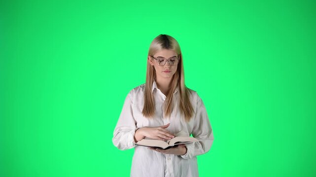 Pretty Blonde Woman Reading a Book, Making Hush Gesture, Studio Shot With Green Background