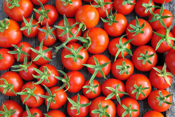 red juicy tomatoes with green tails on a wooden table top view. background of ripe red tomatoes....