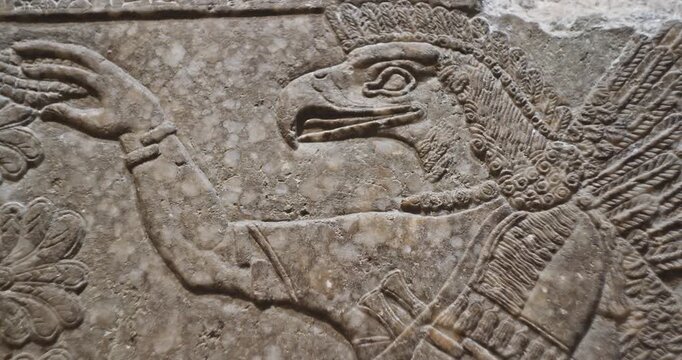 Close-up view on Eagle-headed Winged Figure And Sacred Trees. Architectural Fragment Of Panel From Northwest Palace Of Ashurnasirpal Ii By Neo Assyrian Period. Winged Bird Divine Spirit. Symbol Of