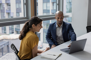 Business colleagues looking at a laptop in an office meeting