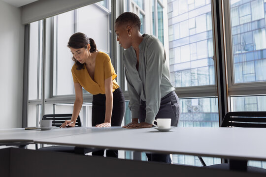 Two female businesswoman standing in a meeting room planning stategy