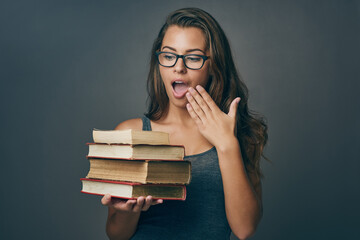 Studying, surprise and books for reading with woman with university, college and library textbook in studio. Wow, knowledge and learning shock of student with education, exam and dark background