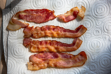 four crispy slices of bacon on a paper towel for breakfast
