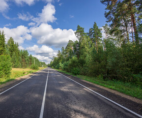 A road with a clear blue sky and trees in the background