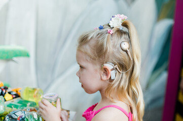 Funny child with cochlear implant walks outdoor. Hearing aid and medicine innovating technology...