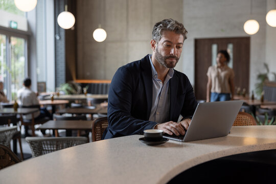 Mature hispanic male businessman working from a restaurant sitting at the counter