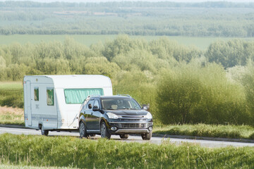 Vehicle hauling caravan through green landscape