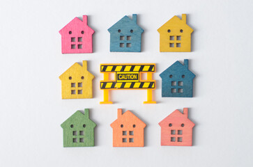 A collection of house models with a warning sign highlights potential risks or cautions associated with property investment