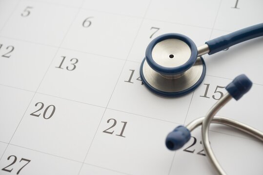 Stethoscope on white blank calendar background. Doctor appointment date reminder in hospital clinic center for health checkup, see condition and treatment. Healthcare, healthy lifestyle concept.