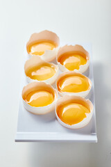 Tray of six eggs with yolks inside. The eggs are arranged in neat row on white stand