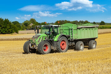 Tractor with loader wagon on the mown grain field - 8457