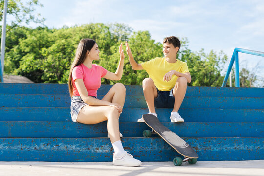 Smiling friends, skaters, teenagers wearing colorful casual clothes giving high five