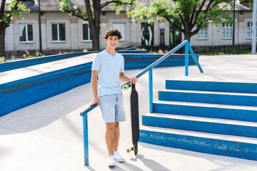 Authentic portrait of smiling teenage boy with braces holding skateboard looking at camera