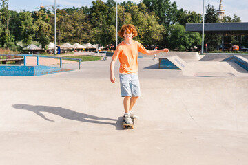 Emotional red haired teenage boy riding skateboard having fun on the street
