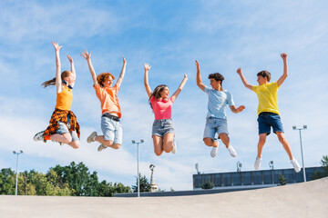 Naklejka premium Group of multiracial overjoyed friends, happy teenagers jumping high, having fun
