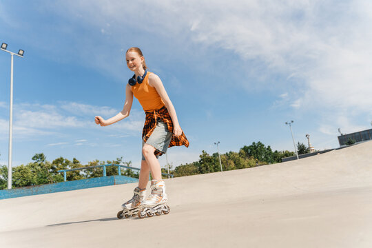 Happy redhead teenager girl on roller skates outdoors in the city