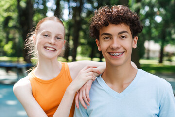 Portrait of happy two teenagers friends embracing posing at the park