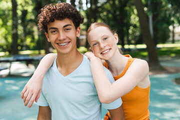 Portrait of attractive red hair girl embracing her male friend outdoors
