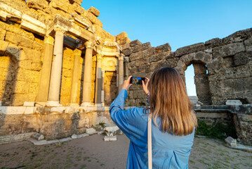 Naklejka premium Female tourist takes a photo of the ruins of an ancient city.