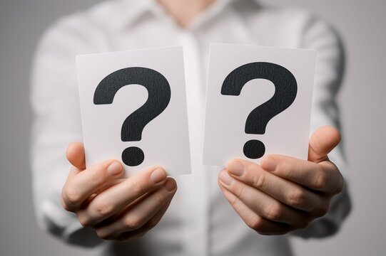 Close-up of a person holding two cards with question marks, symbolizing uncertainty, decision-making, and seeking answers