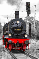 Historic steam locomotive on the Ruhrtalbahn railroad line between Bochum-Dahlhausen and Wetter in the idyllic Ruhr Valley, Germany. Frontal view of old train engine. Black and white with red details. © ON-Photography