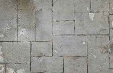 A wet stone pavement with visible water patches, the texture and patterns of the tiles after rainfall