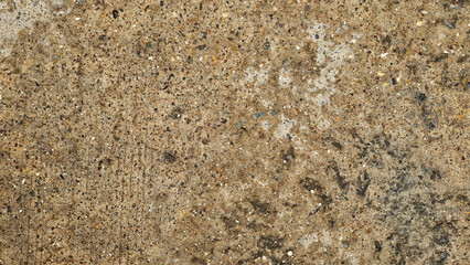 Textured concrete surface embedded with small stones and pebbles, varied appearance of aggregate concrete