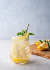 Mojito cocktail with fresh lemon, mint and ice. Refreshing citrus lemonade drink on a light background with wooden board.