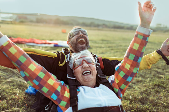 Elderly woman tandem skydiving with instructor, celebrating landing