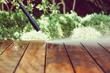 cleaning terrace with a power washer - high water pressure cleaner on wooden terrace surface