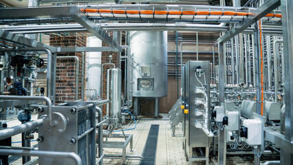 Modern brewery production line with stainless steel tanks and pipes, industrial equipment for beer manufacturing in clean facility.