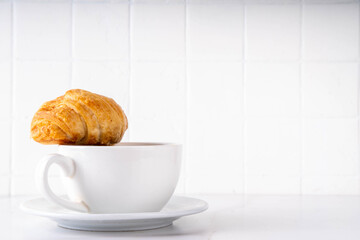 Black espresso coffee cup with croissant