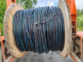 A large bundle of black and blue wires is hanging from a wooden pole