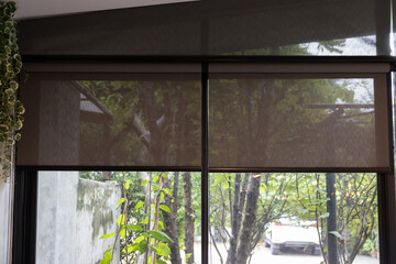 A window with a black blind curtain that is hanging down.