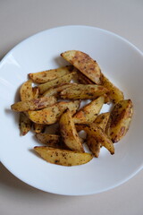 Baked wedges potato on a white plate.