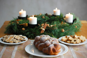 Traditional Czech and Slovak Christmas sweet plaited bread called vanocka (in Slovak vianocka). Christmas pastry on a festively set table, an advent wreath with four burning candles in the background.