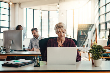Mature woman, business and laptop in office for creative design, email or information of project development. Female person, digital and typing feedback for social media, review report and progress