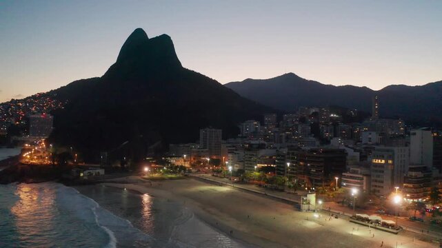 Night aerial view of Leblon in Rio de Janeiro, Brazil, highlighting the beach and surrounding mountains.